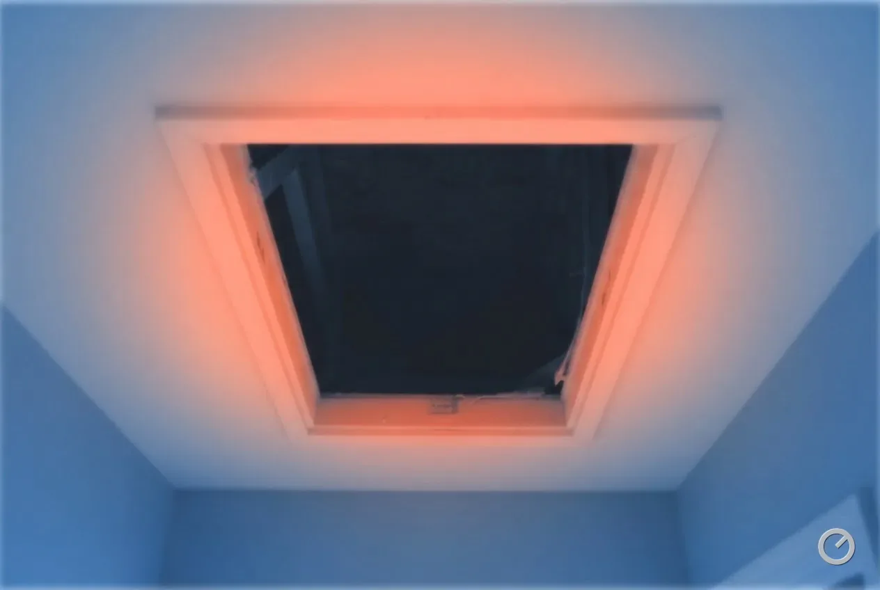 Thermal-toned open attic hatch, its frame warm against a cool room below